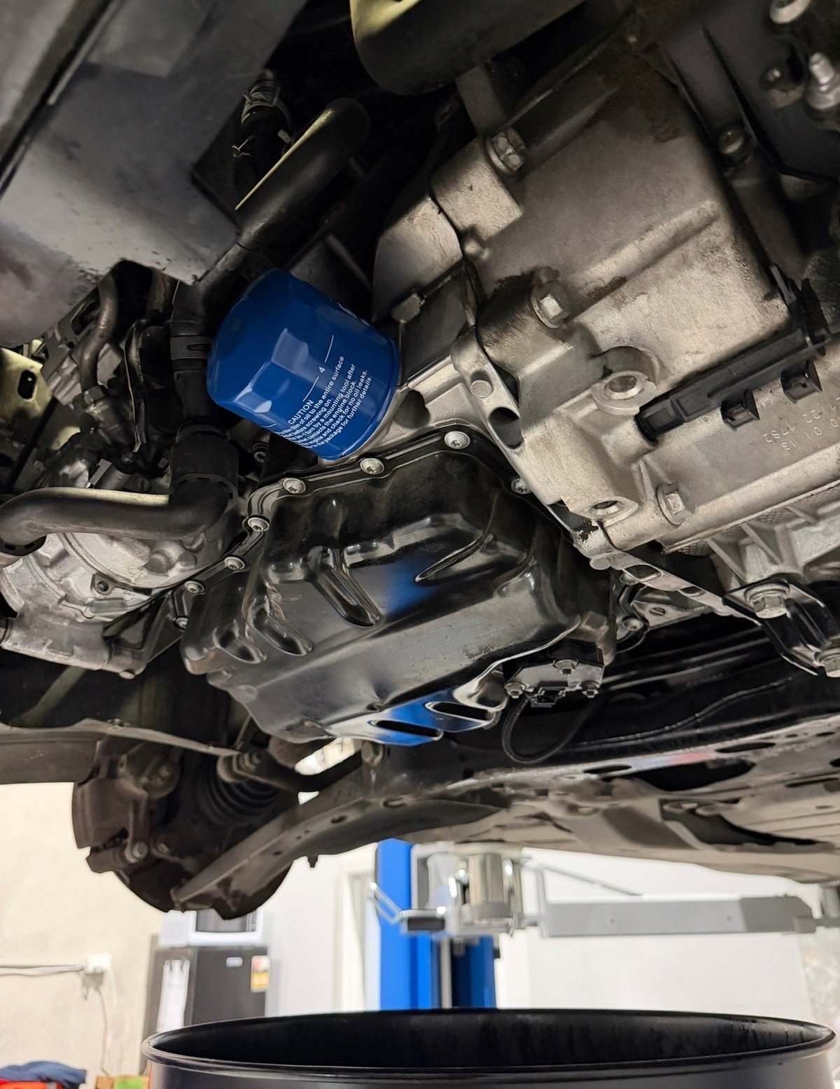 Close-up of car engine undercarriage showing blue oil filter and metallic engine components during maintenance