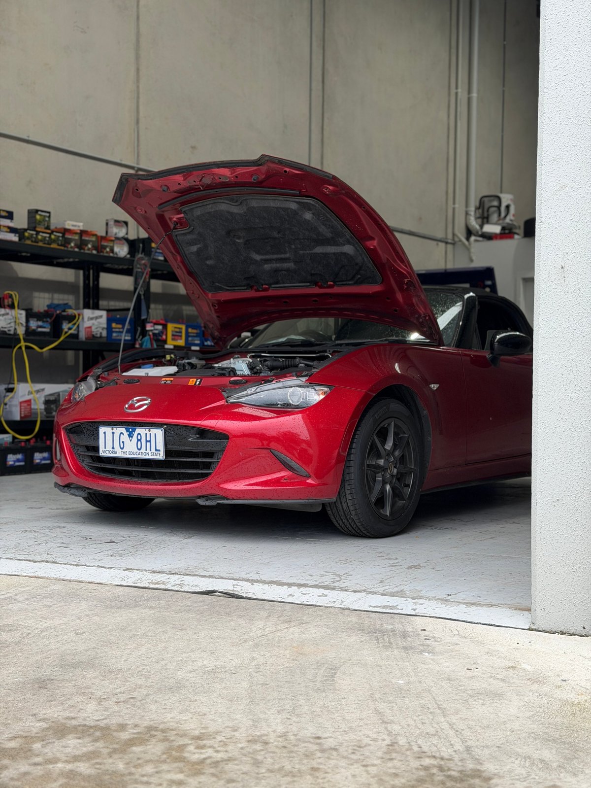 Red sports car with open hood in a garage workshop, displaying engine compartment for maintenance or inspection
